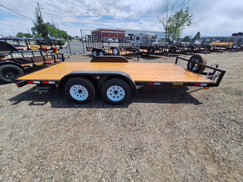 Orange flatbed utility trailer with tandem axles parked on gravel lot