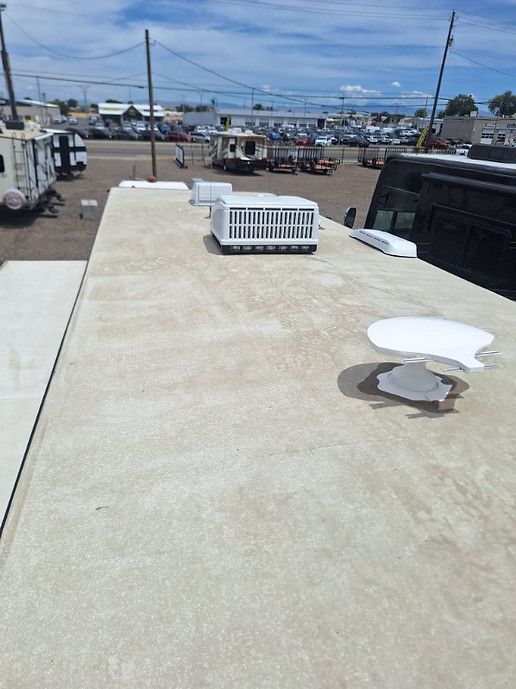 Rooftop with HVAC unit and vents, overlooking a marina and power lines under a blue sky