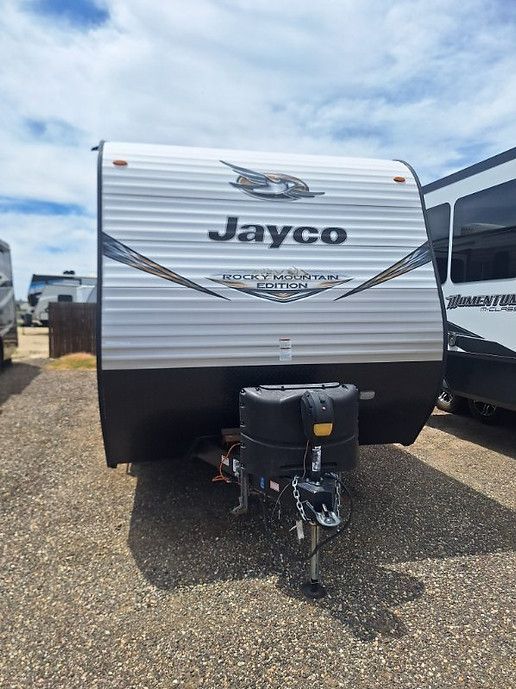 Jayco travel trailer with front hitch and black-and-silver exterior on a gravel lot