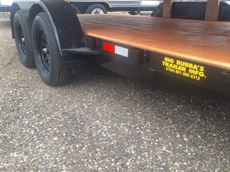 Black dual-axle trailer with wooden deck, red reflectors, and yellow “Big Bubba’s” lettering on the side