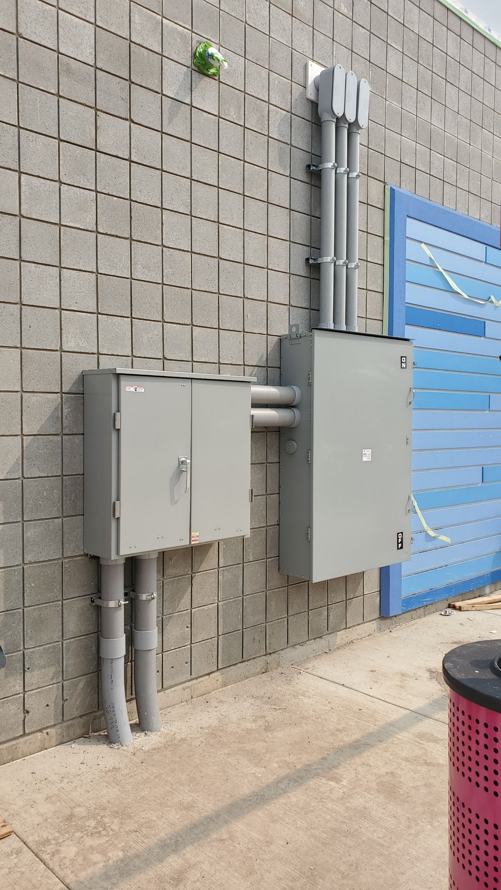 There are two electrical boxes on the side of a building.