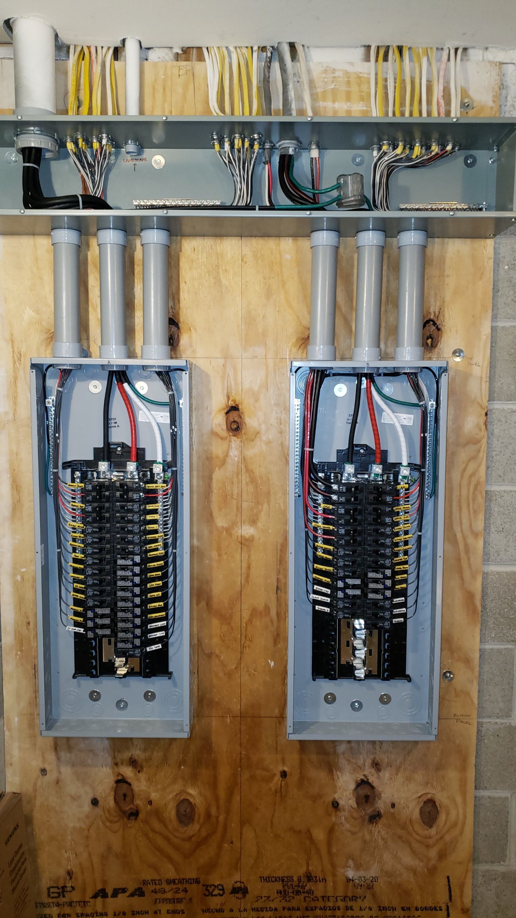 Two electrical panels are hanging on a wooden wall.