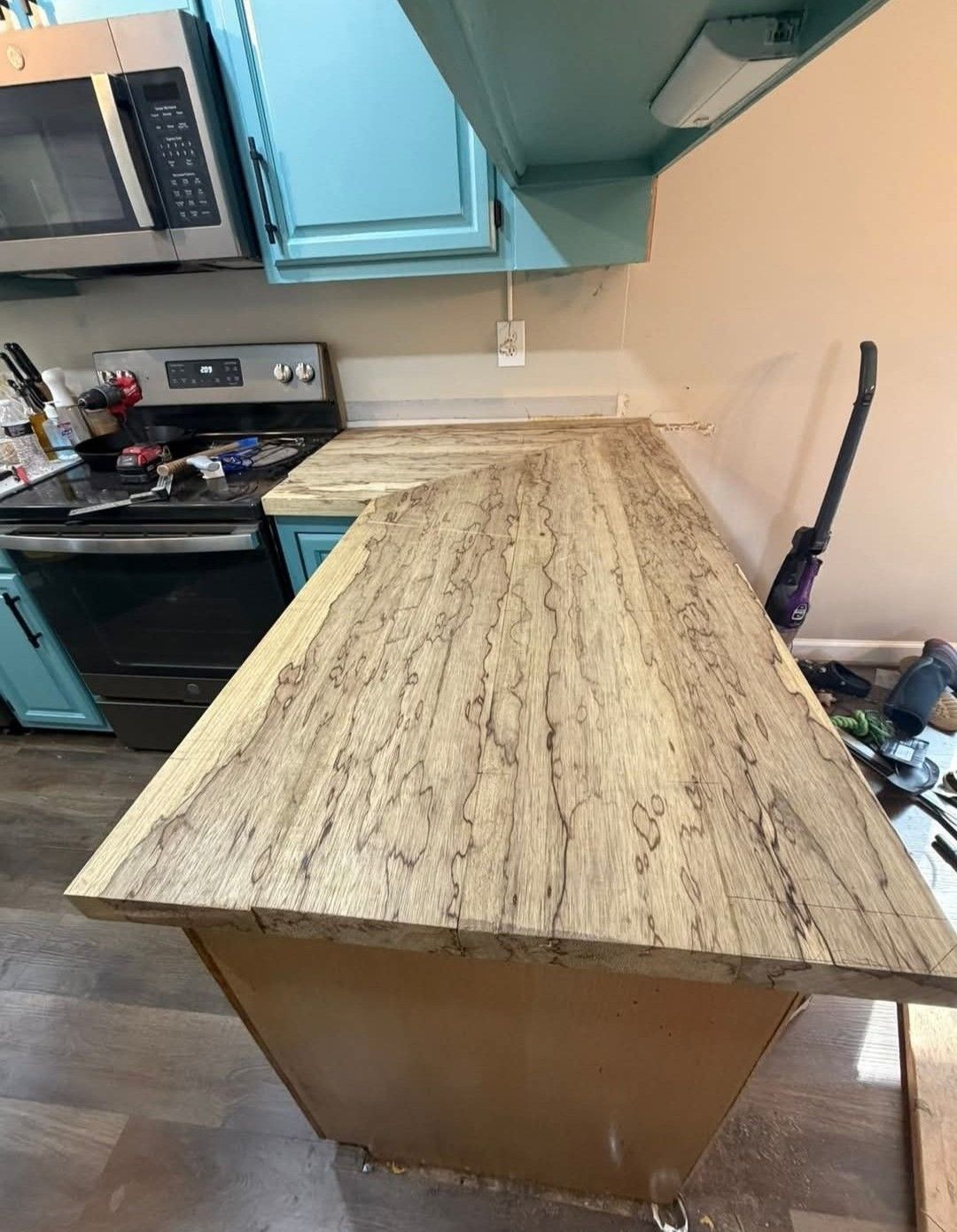 Kitchen with light brown patterned countertop, teal cabinets, and a black oven.
