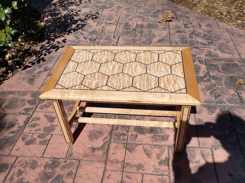 A small wooden table is sitting on a brick sidewalk