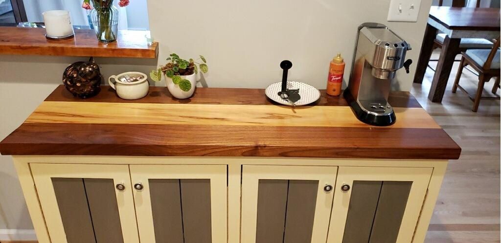 A kitchen counter with a wooden top and a coffee maker on it.