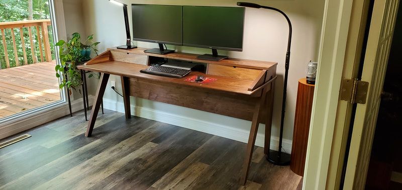 A wooden desk with a computer on top of it in a room.