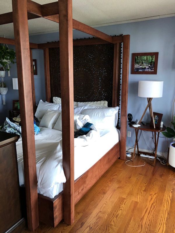 A bedroom with a four poster bed and a lamp