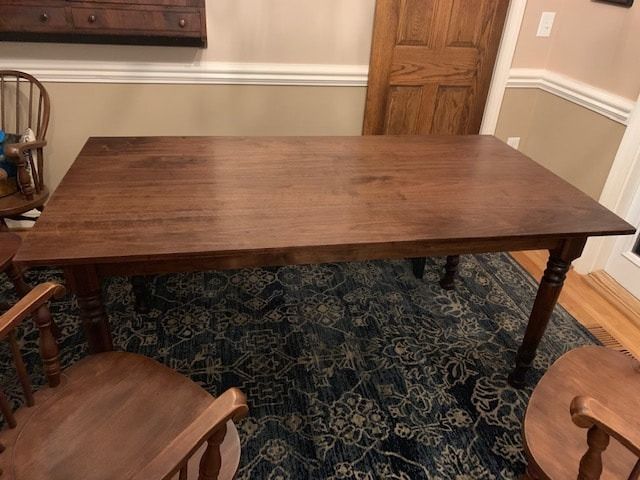 A wooden table and chairs are sitting on a rug in a dining room.