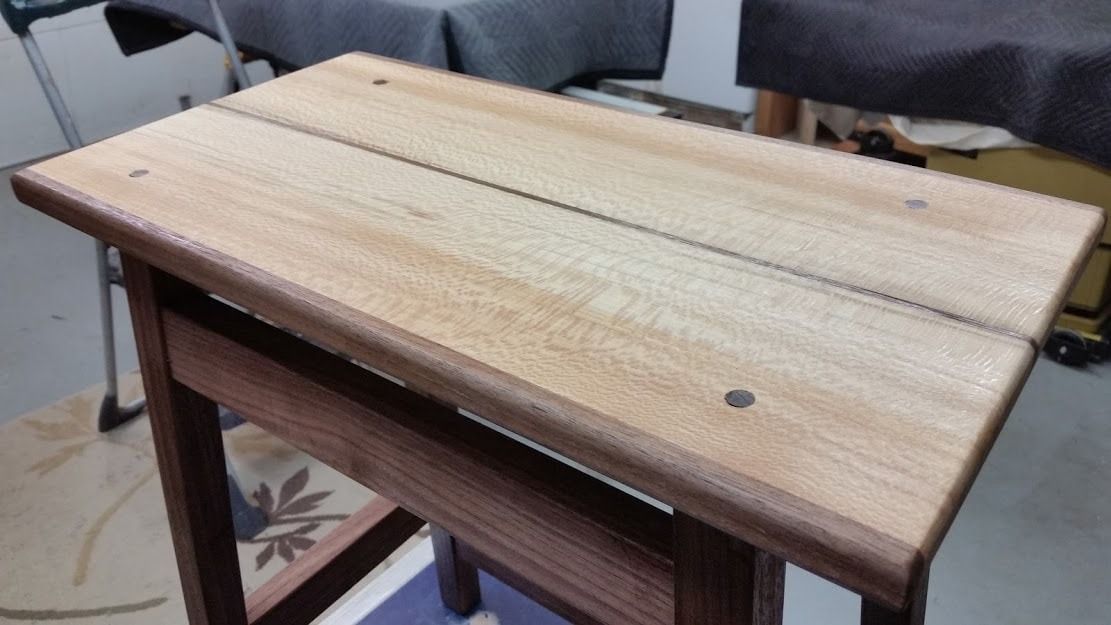 A wooden stool is sitting on a table in a room