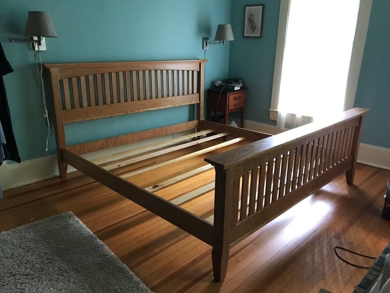 A wooden bed frame in a bedroom with blue walls