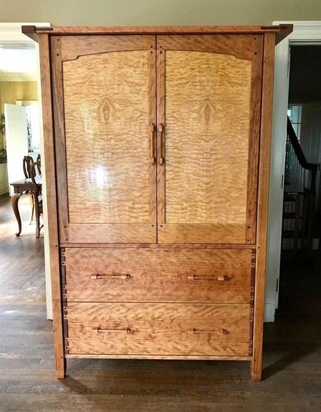 A wooden cabinet with drawers is sitting in a room next to a door.