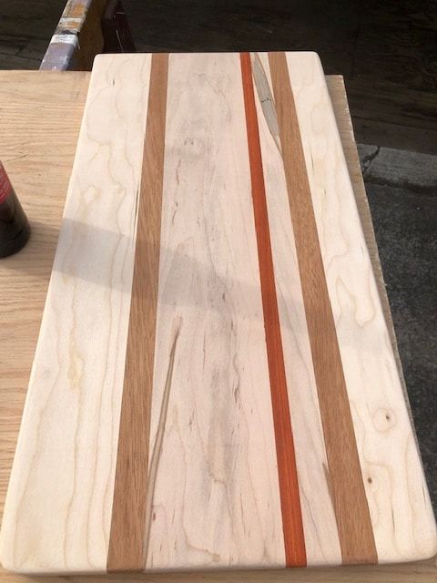 A wooden cutting board with three stripes on it is sitting on a wooden table.