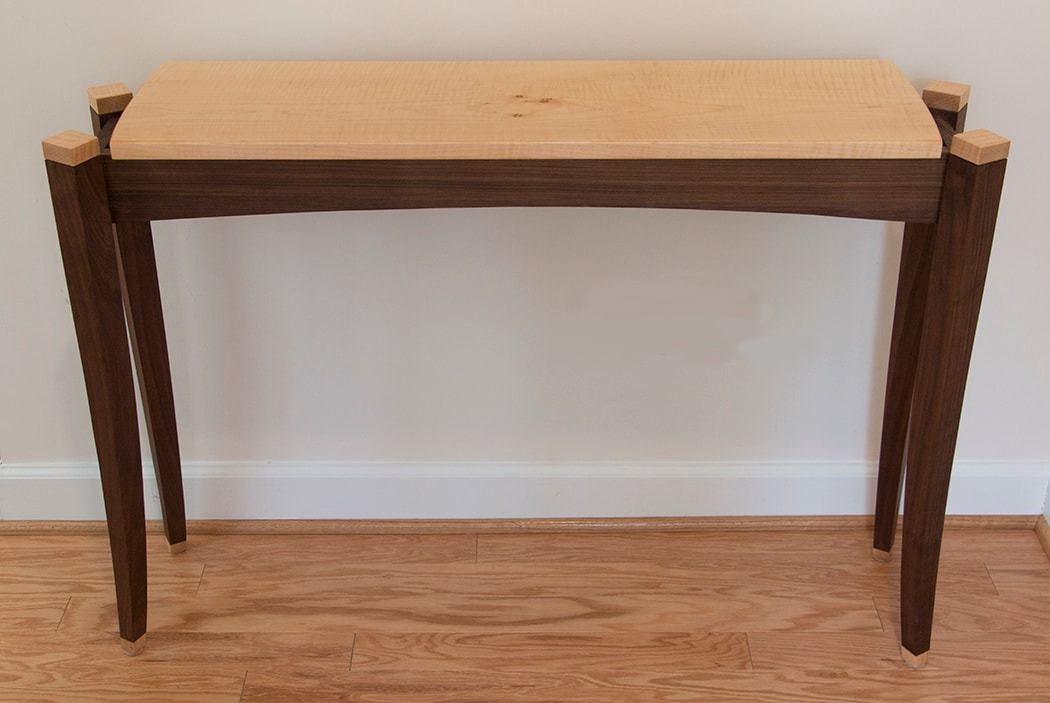 A wooden table is sitting on a wooden floor next to a wall.