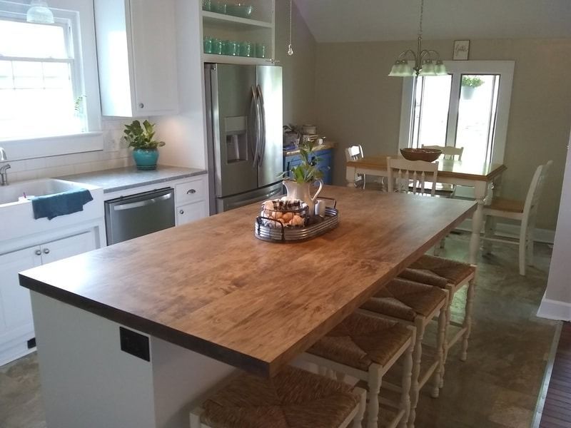 A kitchen with a large wooden table and stools