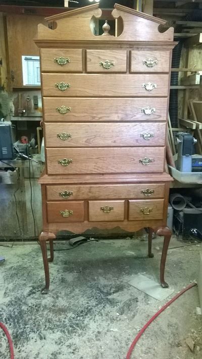 A wooden chest of drawers is sitting on top of a wooden table.