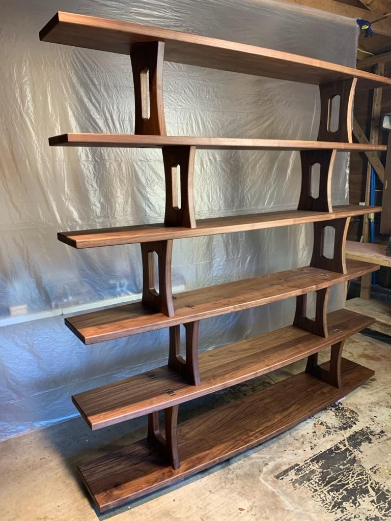 A wooden bookshelf is sitting on the floor in a room.