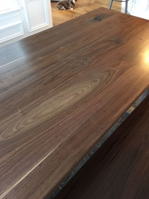 A cat is sitting on a wooden table next to a bench.