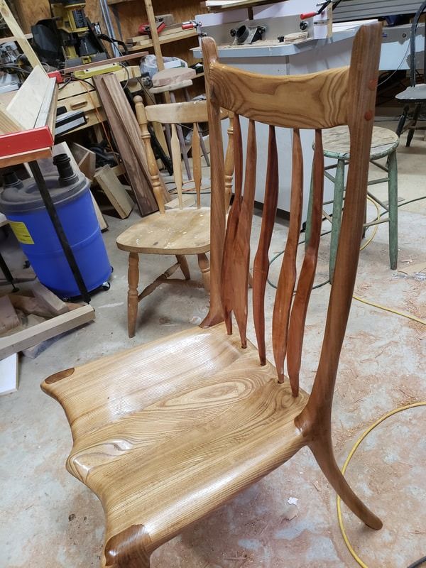 A wooden chair is sitting on the floor in a workshop.