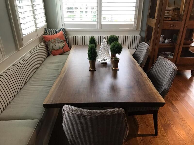 A dining room table with a bench and chairs in front of a window.