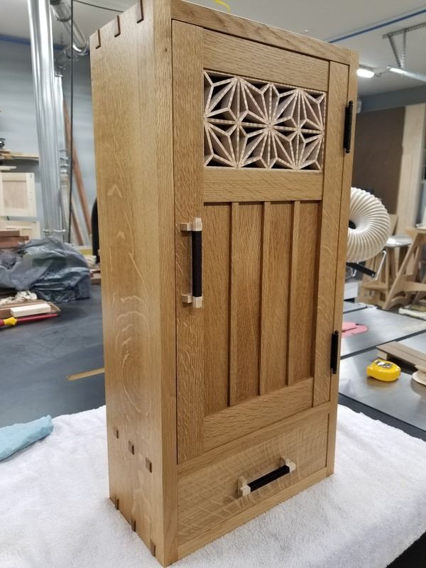 A wooden cabinet is sitting on top of a white towel on a table.