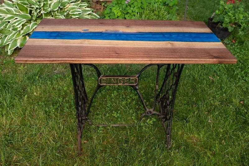 A wooden table with a blue stripe on it is sitting in the grass.