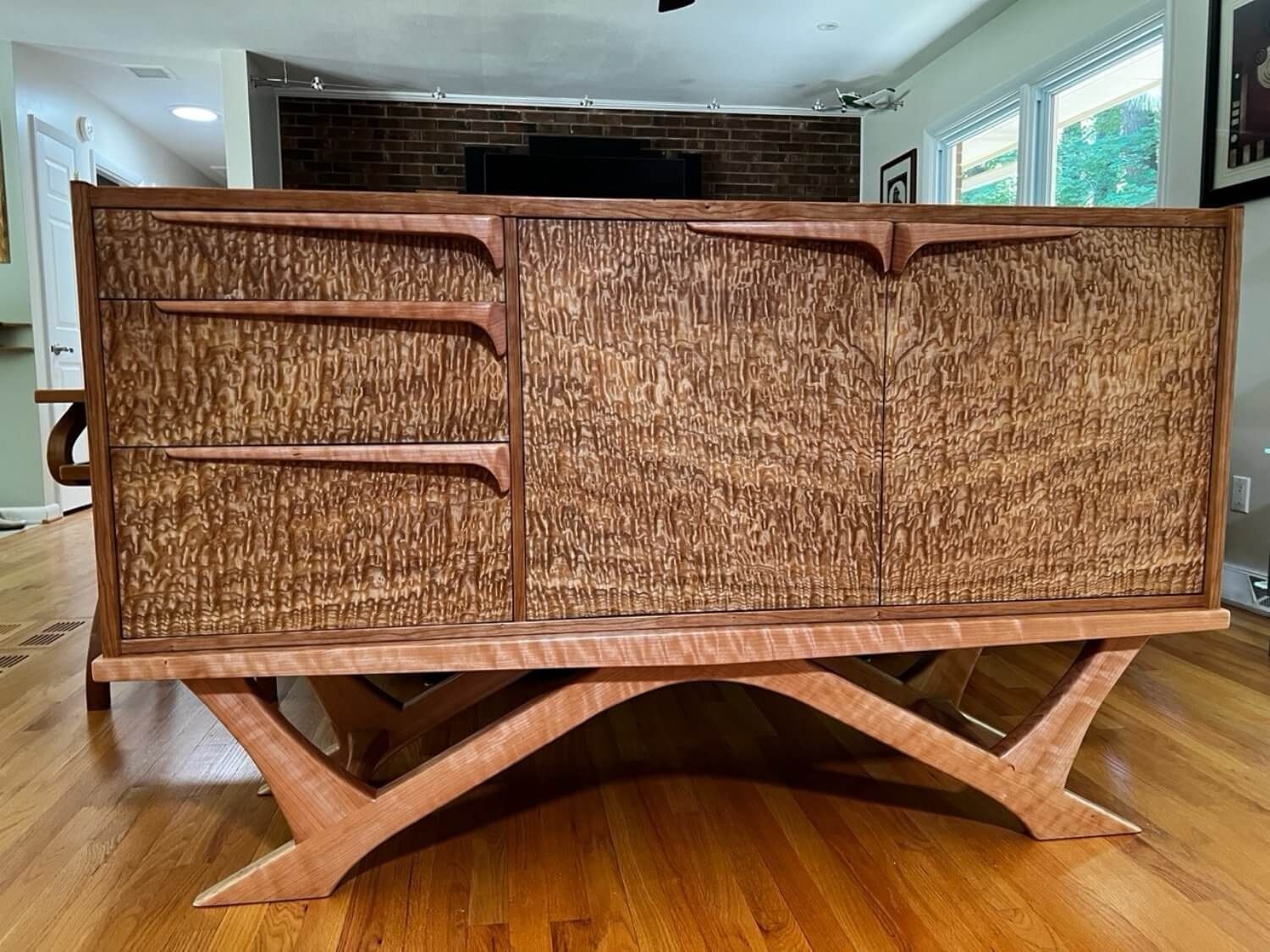 A wooden dresser is sitting on a wooden floor in a living room.