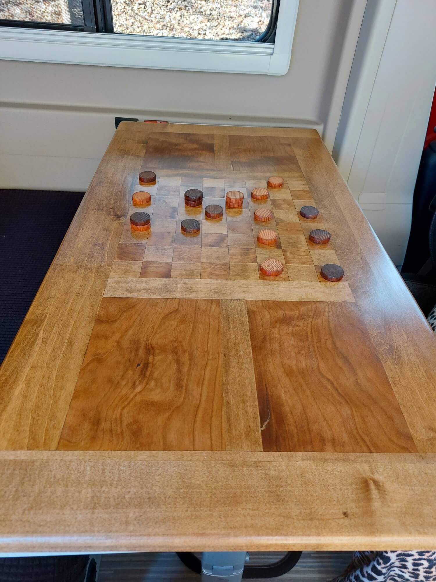 A wooden table with a checkers board on it.