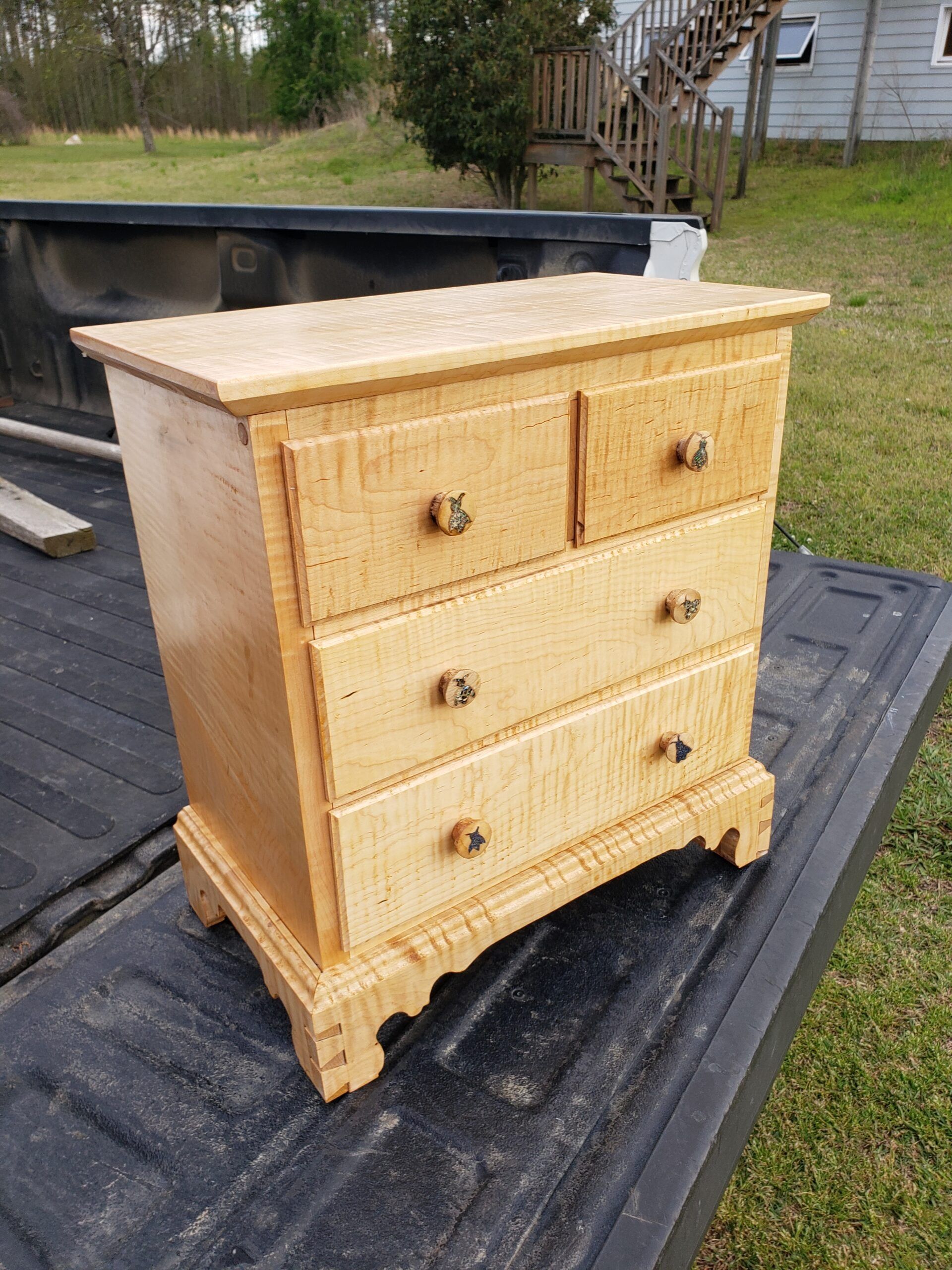 A small wooden dresser is sitting on the back of a truck.