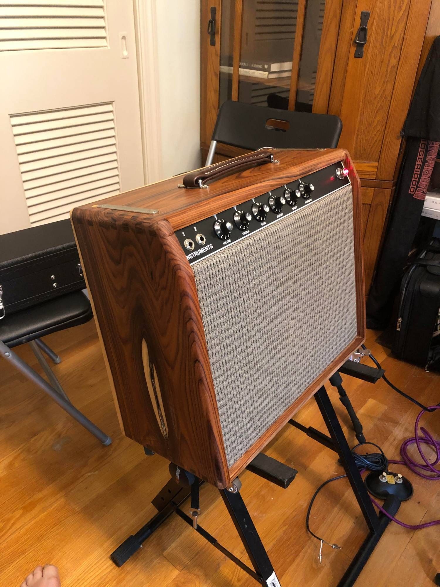 A guitar amplifier is sitting on a stand in a room.