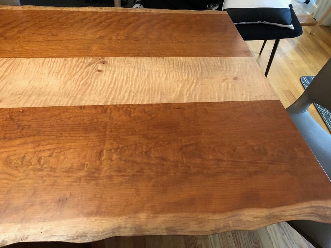 A close up of a wooden table with a chair in the background.
