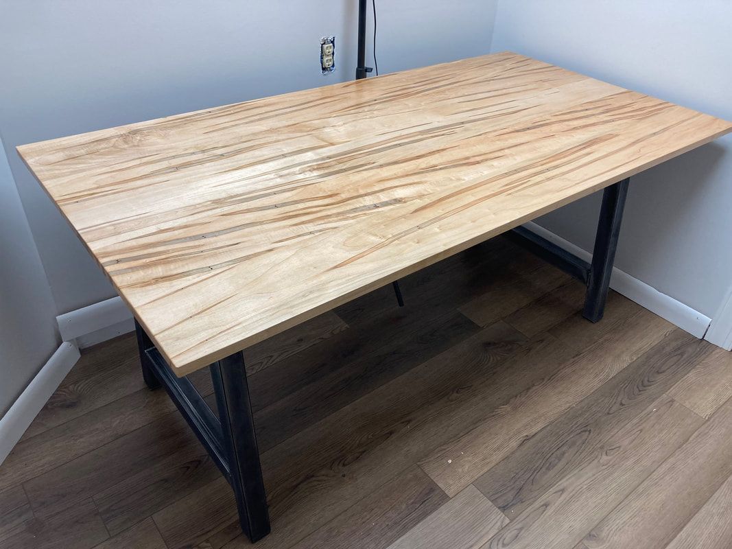 A wooden table with metal legs is sitting on a wooden floor in a room.