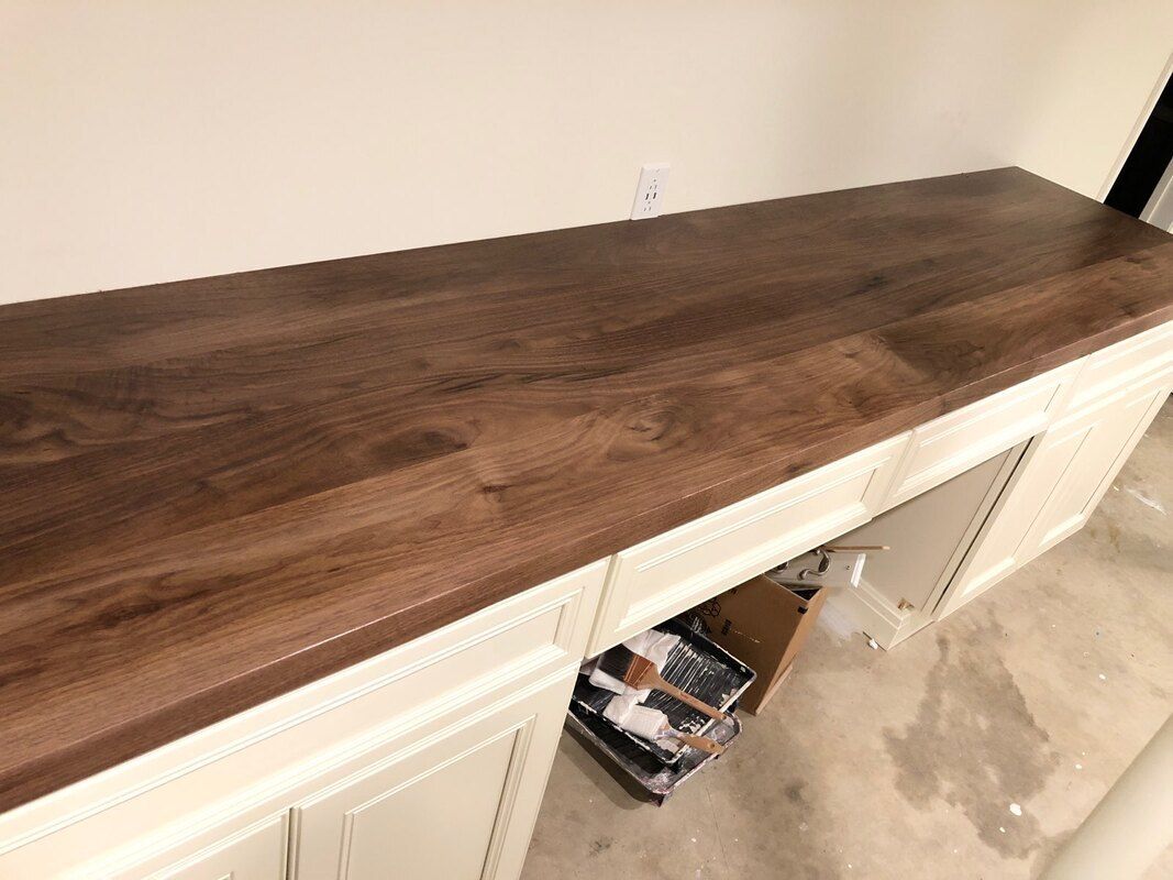 A wooden counter top is sitting on top of a white cabinet.