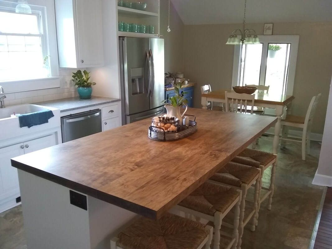 A kitchen with a large wooden table and stools