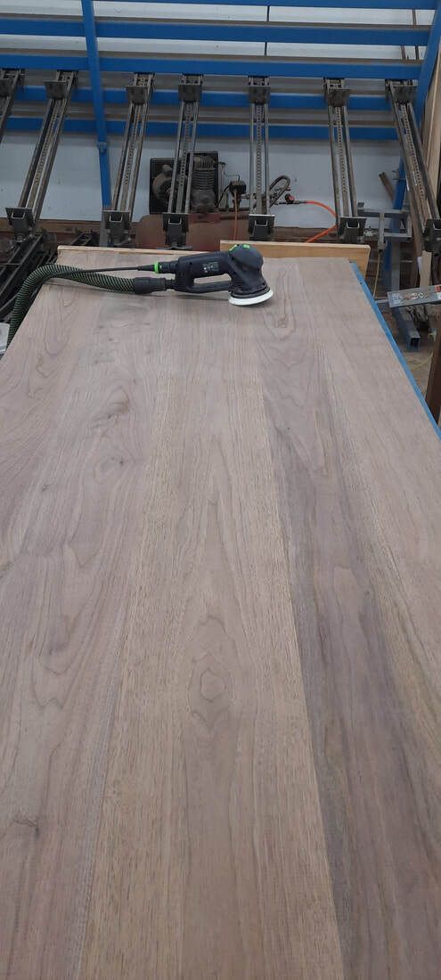 A person is sanding a piece of wood in a workshop.