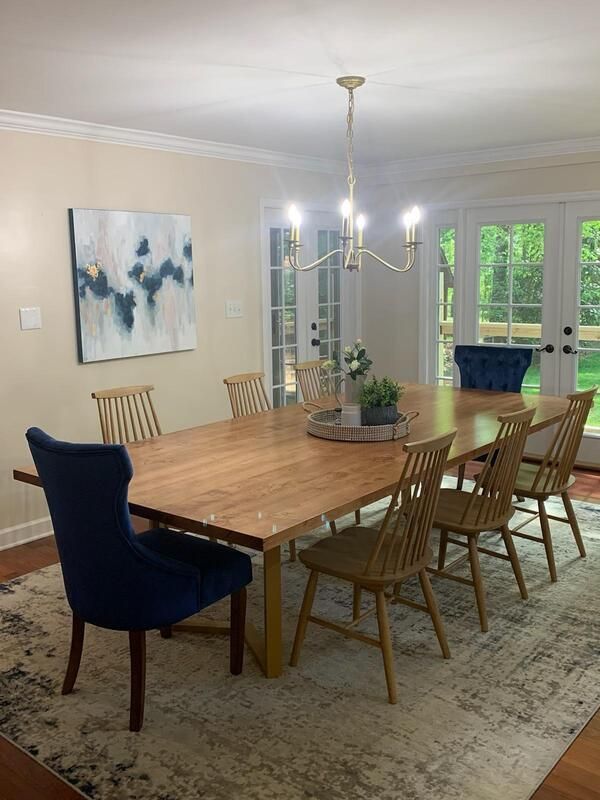 A dining room with a wooden table and chairs and a chandelier.
