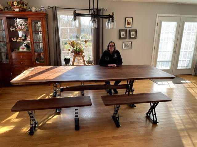 A woman is sitting at a table with two benches in a living room.