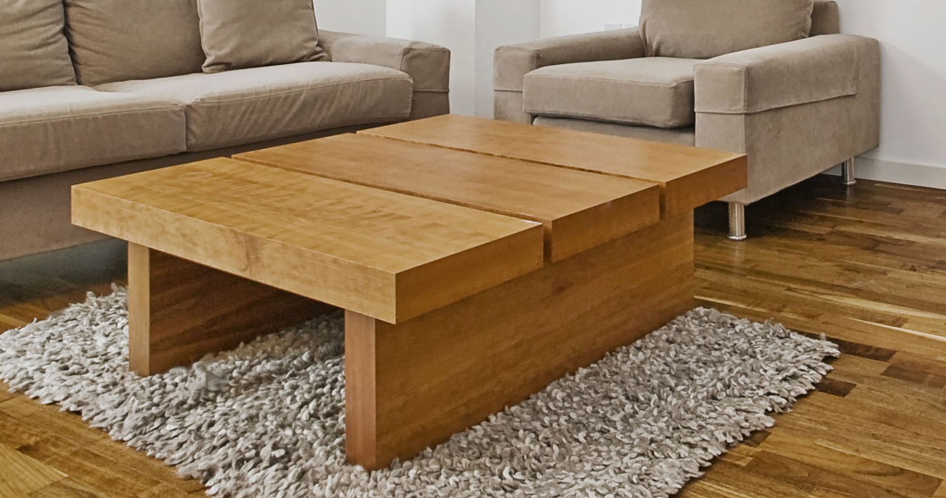 A wooden coffee table in a living room next to a couch and chair