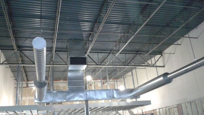 HVAC ductwork and piping installed on a building's ceiling, with exposed metal framing.