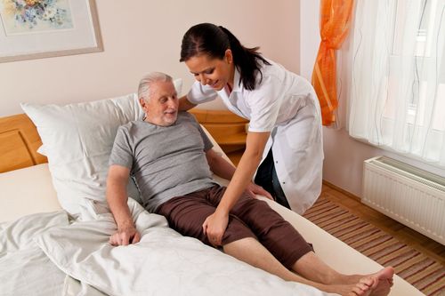 Caregiver assisting a patient in bed in a bright bedroom