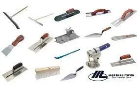 Variety of trowels and tools for masonry work, spread out on a white surface.