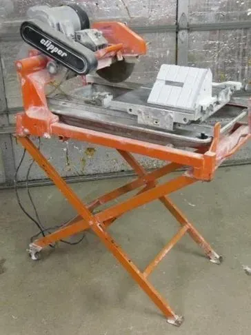Orange tile saw on a folding stand. Clipper brand saw with a diamond blade ready to cut.