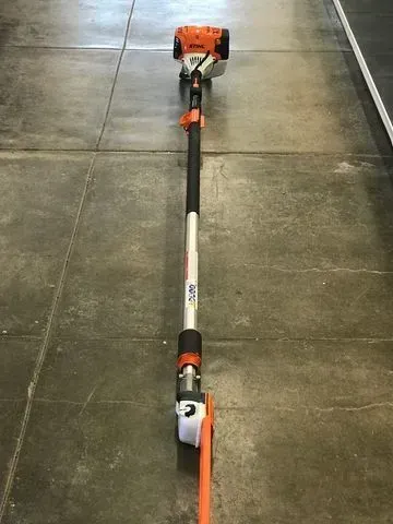 Orange and black telescoping pole saw on a concrete floor.