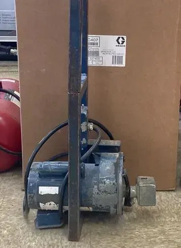 Blue electric motor mounted in a metal frame, in front of a cardboard box.