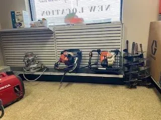 Tools and equipment on display inside a shop. Includes a generator, tampers, and a pump.