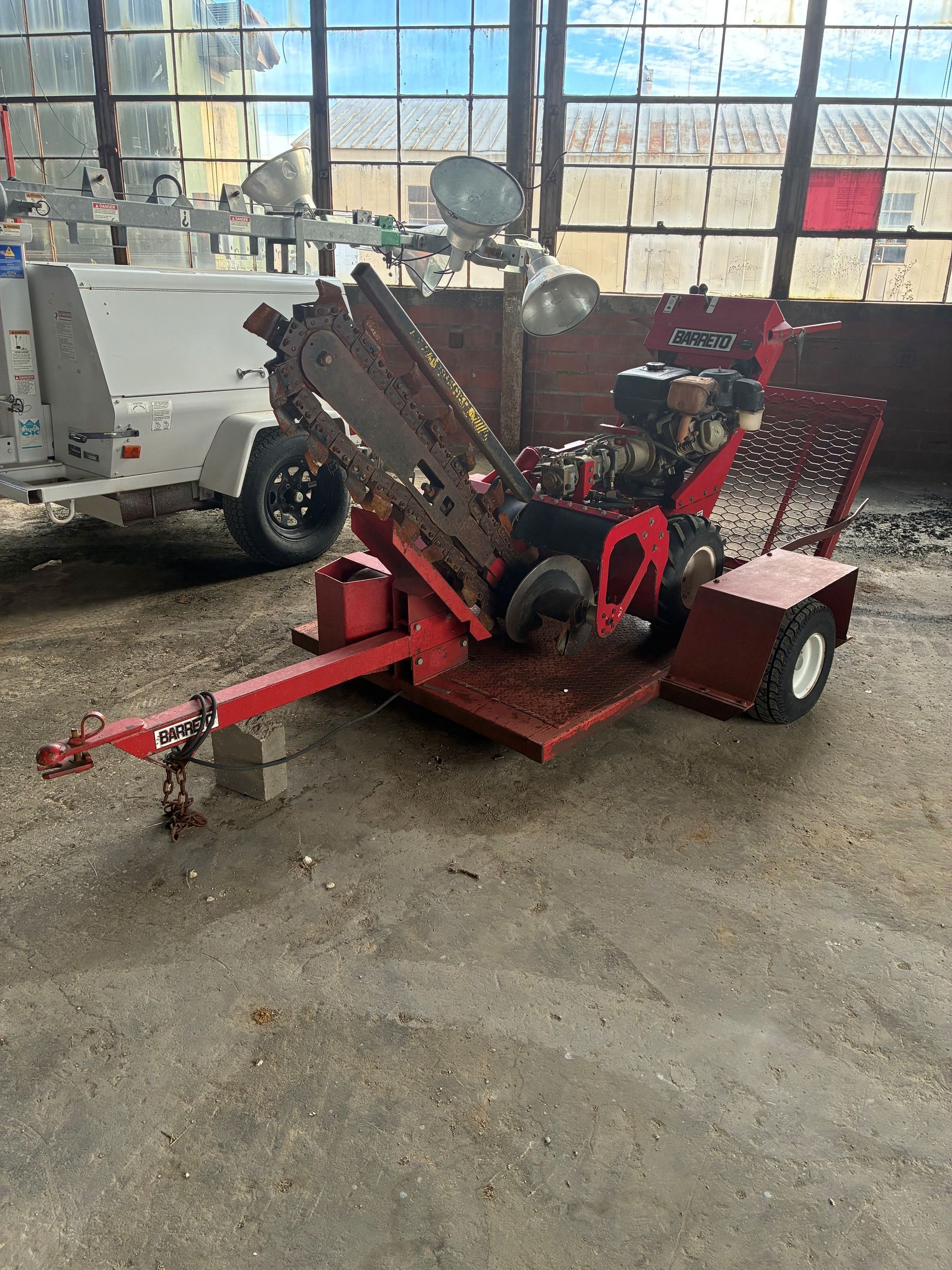 Red stump grinder with trailer parked inside a building.