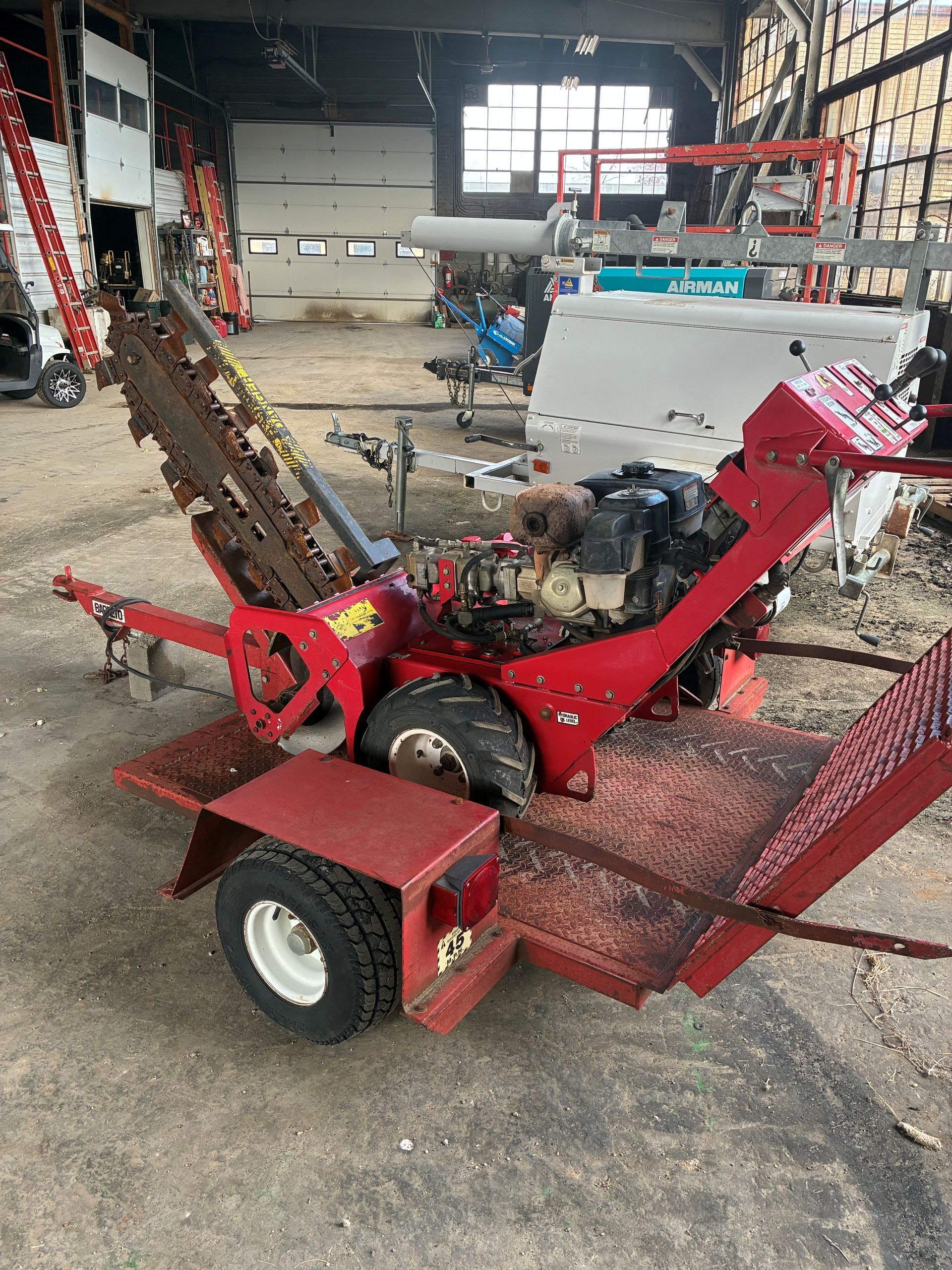 Red trenching machine on trailer, outdoors.