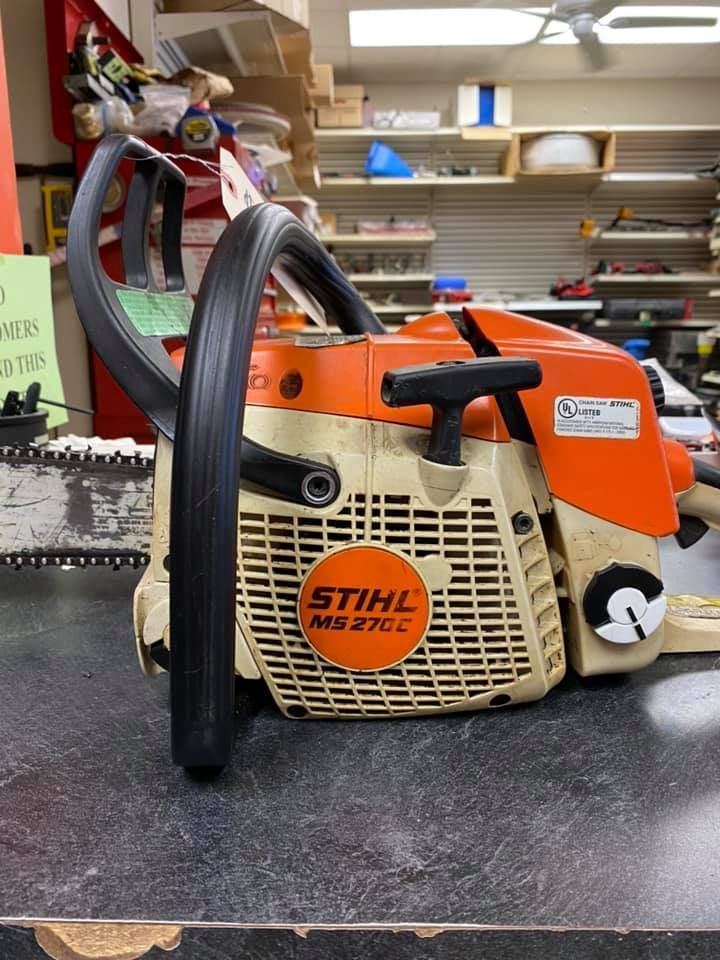 Stihl MS 271 C orange and beige chainsaw on a workbench in a workshop.