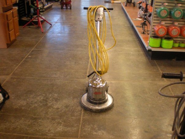 Floor buffer with a yellow cord on a concrete floor.