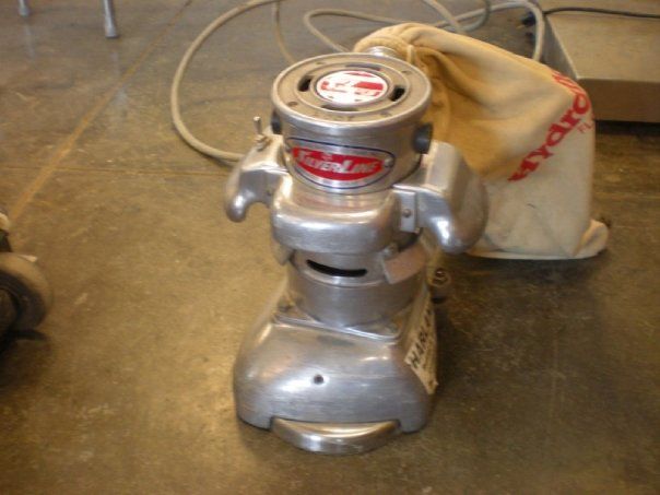 Floor sander with dust bag on a concrete floor.