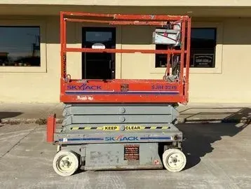 Orange Skyjack lift in front of a building.